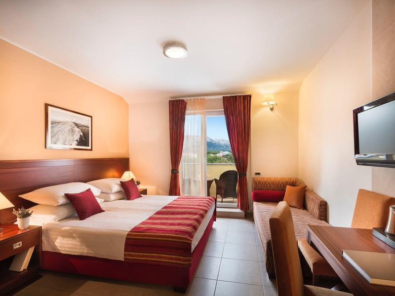 Chambre d'hôtel confortable avec lit double, bureau et balcon avec vue sur la nature.