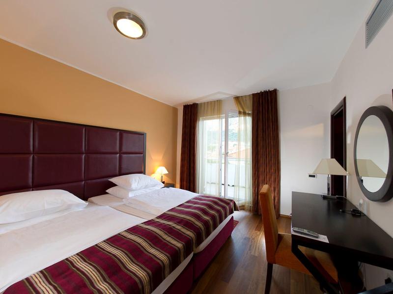 Chambre d'hôtel confortable avec lit double, bureau et grande fenêtre donnant sur l'extérieur.