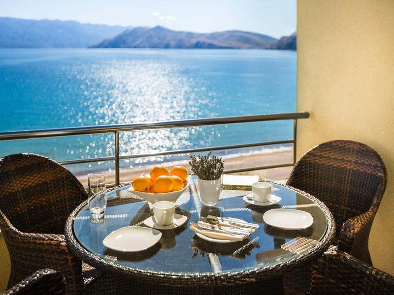 Table de balcon avec deux chaises, thé et oranges avec vue sur la mer et les montagnes.