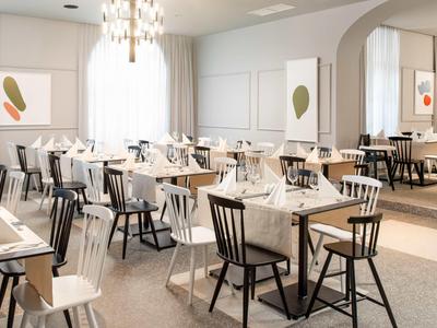 Elegant restaurant met wit gedekte tafels, gemengde stoelen en moderne verlichting.