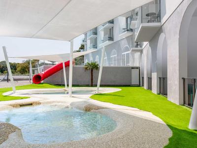 Modern hotel speeltuin met waterpartijen, rode glijbaan en kunstgras