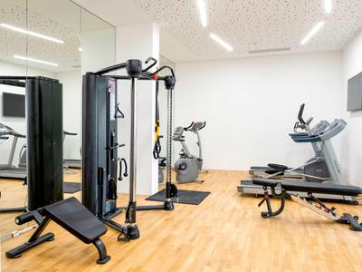 Moderne fitnessruimte met trainingsapparatuur en lichte houten vloer in een hotel.
