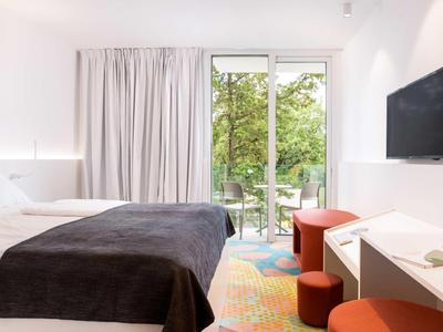 Moderne hotelkamer met bed, flatscreen-tv en uitzicht op groene buitenruimte