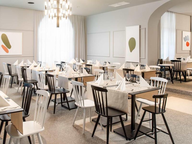 Elegant restaurant with white set tables and modern decor.