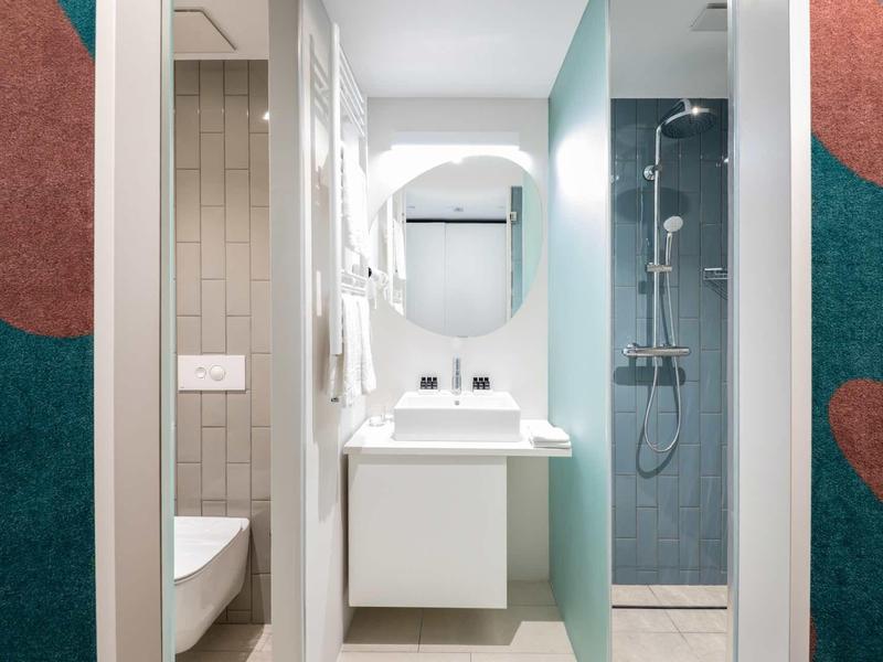 Modern hotel bathroom with sink, mirror, and shower area.