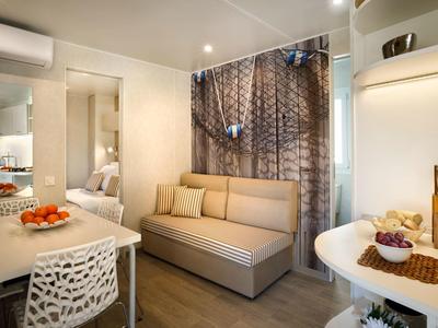 Zona soggiorno accogliente in hotel con divano, tavolo da pranzo e decorazioni moderne.