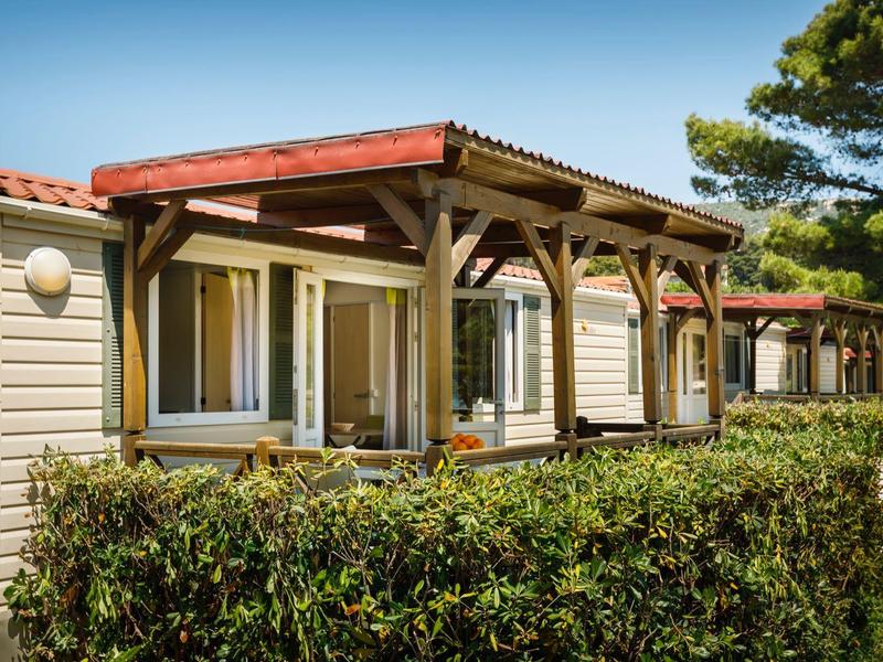 Casa mobile con veranda vetrata circondata da siepe in posizione soleggiata.