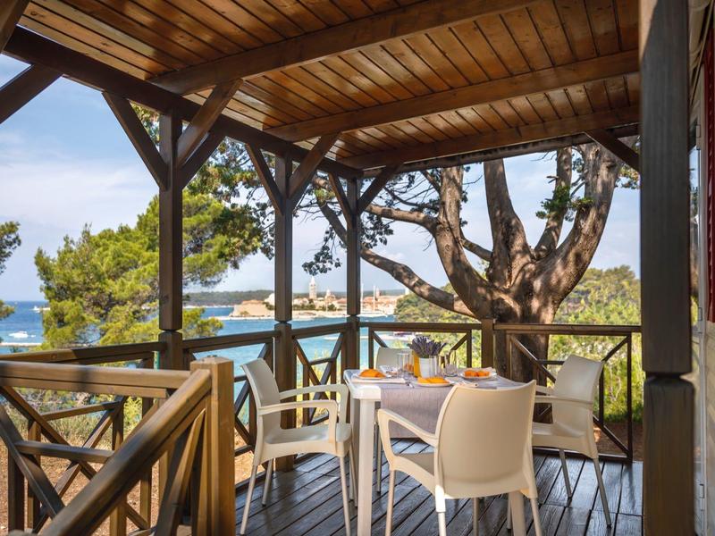 Terrazza coperta con pavimento in legno e area salotto con vista sul mare.