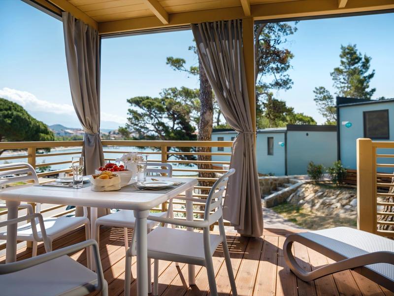 Terrazza con tavolo e sedie, vista su alberi e edifici sullo sfondo
