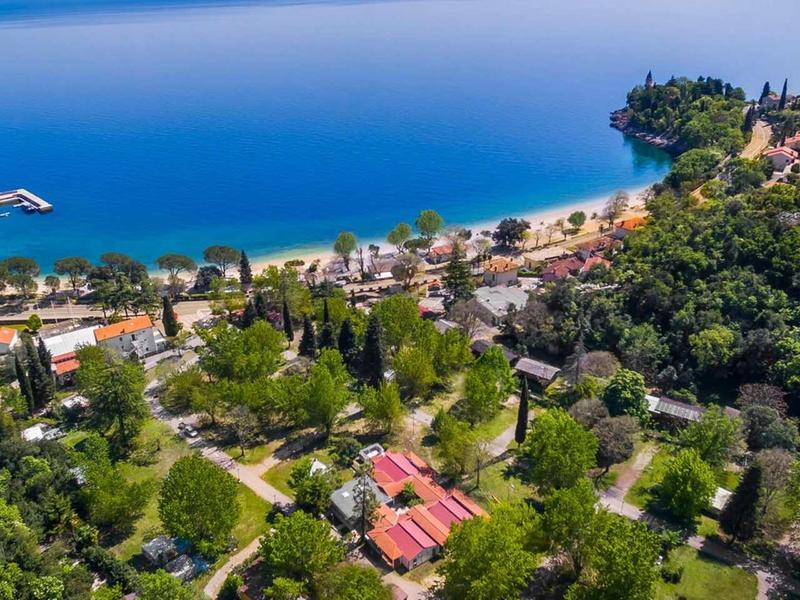 Aerial view of coastal village with beaches, wooded hills, and buildings