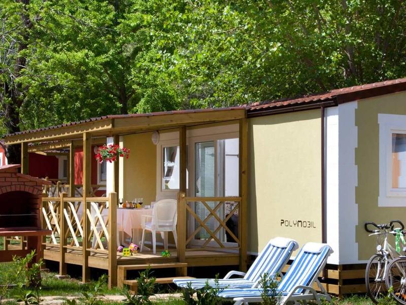 Cozy holiday cabin with porch, deck chairs, and bicycles in a green setting.
