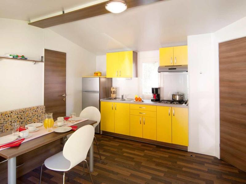 Modern kitchen and dining area with yellow cabinets and cozy seating nook.