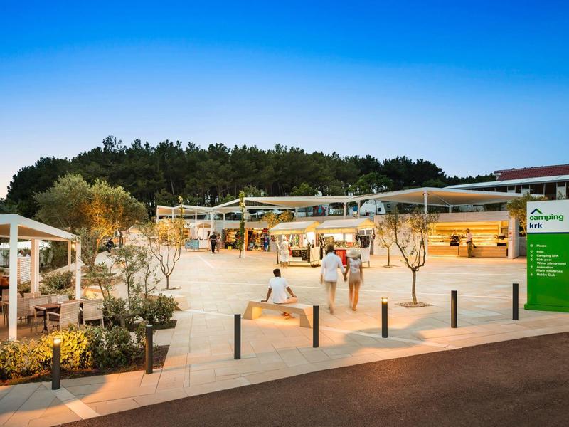 Modern campsite at sunset with tents and people relaxing outdoors.