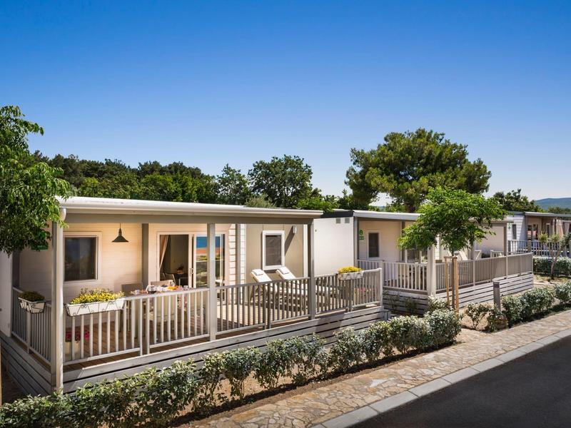 Modern bungalows with terrace and garden in a quiet holiday resort under clear sky.