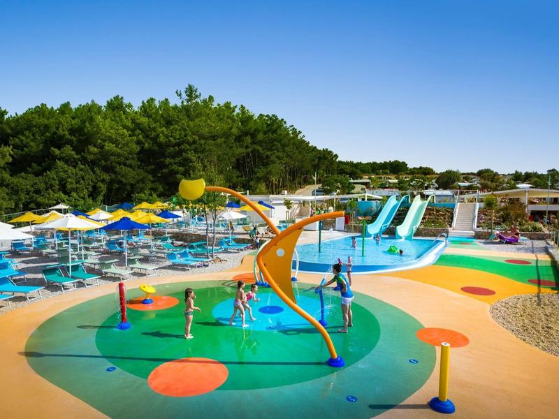 Colorful water playground with slides and sun umbrellas under clear sky in a holiday resort.
