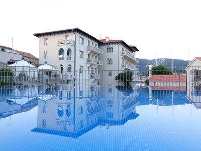 Hotelgebouw met raamgevel weerspiegeld in het heldere blauwe water van een zwembad.
