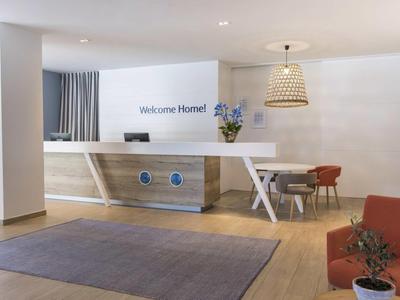 Moderní hotelová recepce s pultem, sezením a uvítacím nápisem.