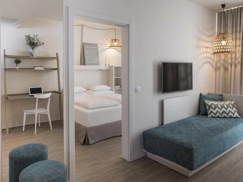 Nowoczesny pokój hotelowy z częścią dzienną i sypialną, jasny i przyjazny.