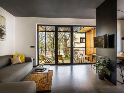 Modern living room with gray sofa and large windows overlooking terrace and garden.
