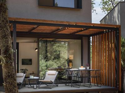 Modern outdoor area with wooden canopy and cozy seating in front of a large window.