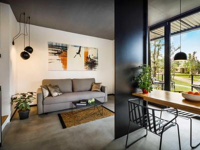 Modern living area with sofa, artwork, plants, and dining space overlooking garden.