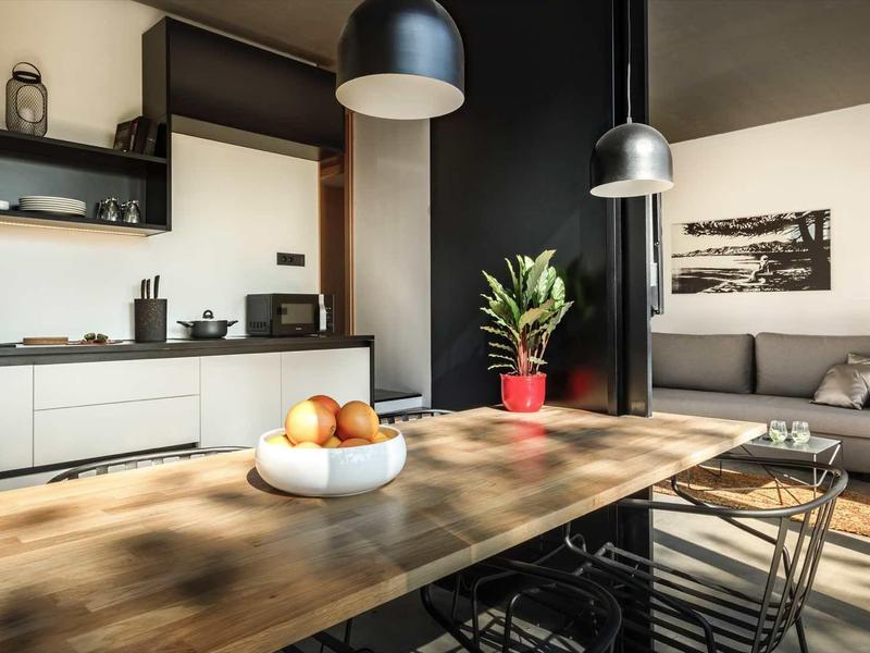 Modern open kitchen and living room with large wooden table and natural light.