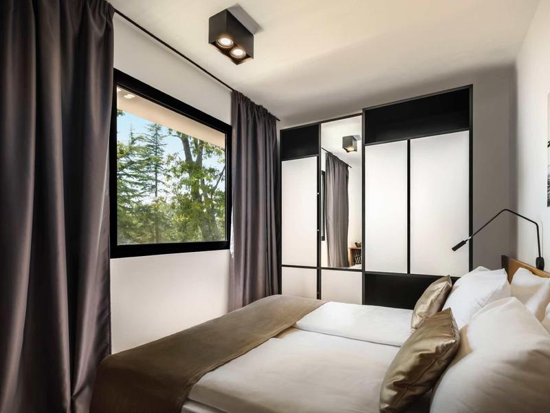 Modern bedroom with large window, curtains, and spacious wardrobe.