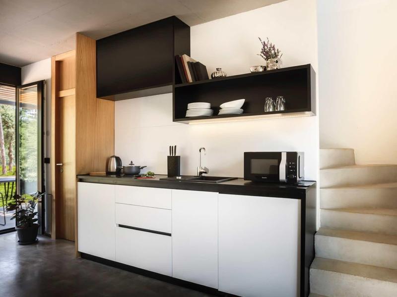 Modern kitchen unit with black and white cabinets and access to the balcony.