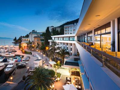 Pohled na marinu při západu slunce s moderním hotelem a terasou.