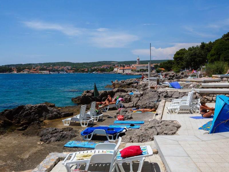 Área costera con tumbonas y protección solar junto al mar bajo un cielo despejado.