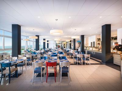 Velký restauranční prostor s moderními stoly a židlemi, jasné osvětlení