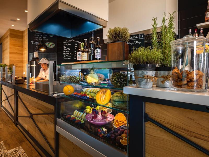 Modern cafeteria with cakes, fresh herbs, and drinks in a stylish wooden counter.