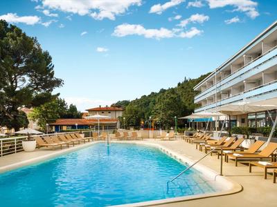 Moderner Hotelpool mit Liegestühlen und umgebender Natur an einem sonnigen Tag