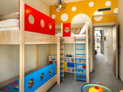 Brightly furnished children's room with bunk bed, colorful wooden elements, and storage space.