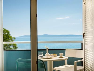Balcony with table and chairs overlooking the sea and an island on the horizon.