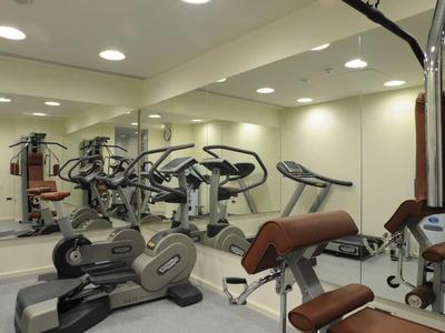 Fitnessraum mit modernen Trainingsgeräten und Spiegelwand in einem Hotel.