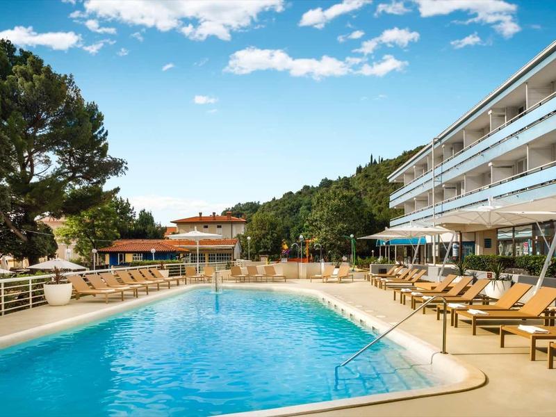 Modern hotel pool with sun loungers and a view of a blue sky