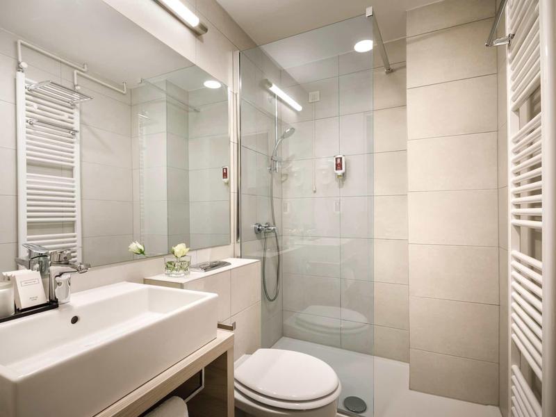 Modern, bright bathroom with shower, sink, and toilet in neutral tones.