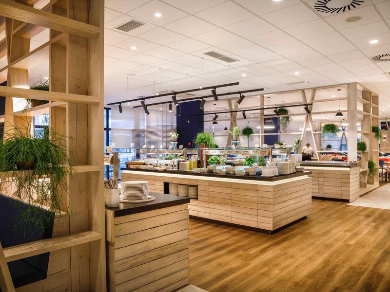 Modern buffet area with wood and plant decor in a hotel restaurant.