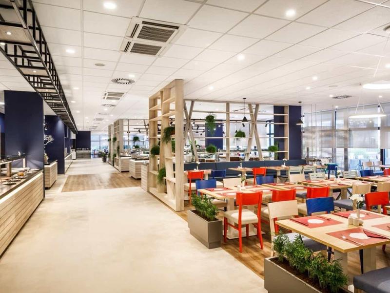 Bright, modern dining area with colorful chairs and buffet section in a hotel.