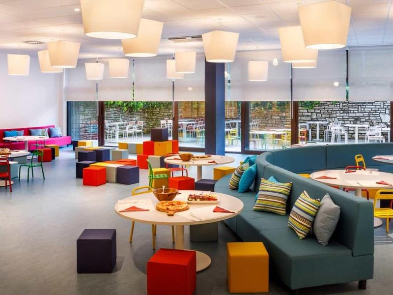 Modern hotel lounge with colorful seating and large windows overlooking the street.