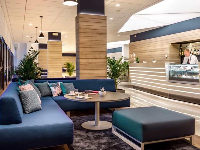 Modern hotel lounge with blue sofas, a round table, and wood accent walls.