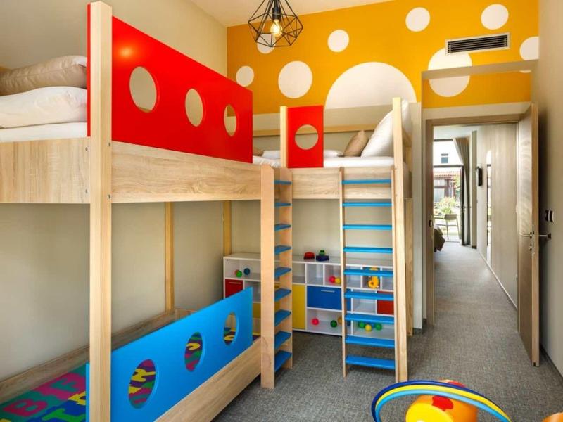 Brightly furnished children's room with bunk bed, colorful wooden elements, and storage space.