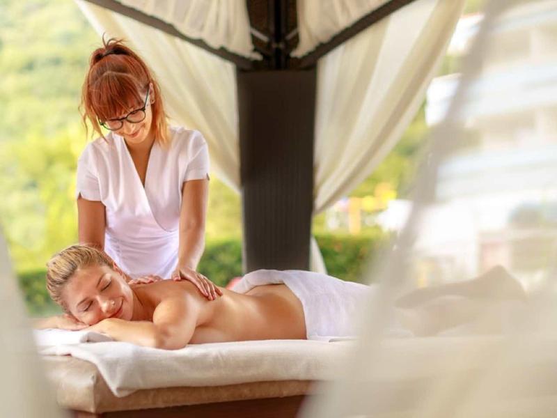 Woman receiving relaxing outdoor massage under gazebo with green landscape background