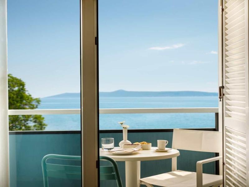 Balcony with table and chairs overlooking the sea and an island on the horizon.