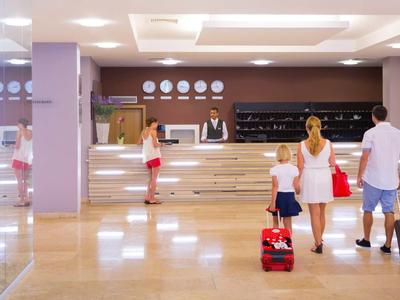 Ein Hotel-Empfangsbereich mit Kunden, Rezeptionisten und moderner Einrichtung in hellem Licht.