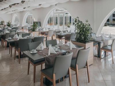 Hell gestalteter Speisesaal mit eingedeckten Tischen und modernem Mobiliar.