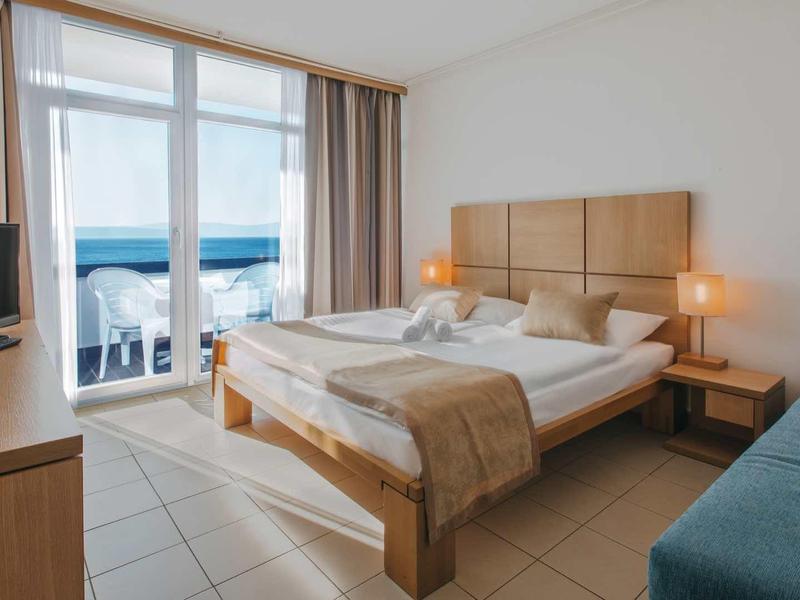 Bright hotel room with double bed and sea view from the balcony.