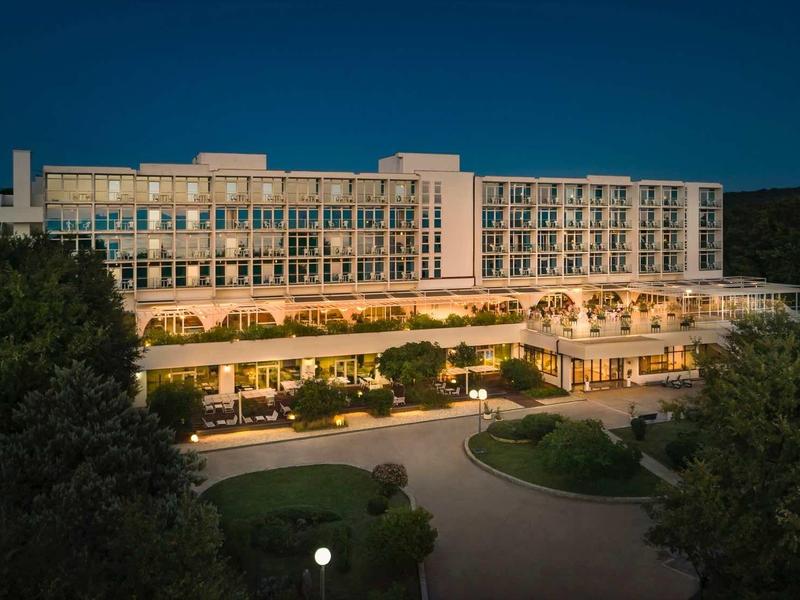 Illuminated multi-story hotel building at night surrounded by trees.