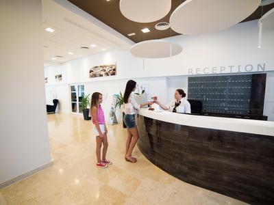 Moderne Hotelrezeption mit Empfangspersonal und wartenden Gästen.